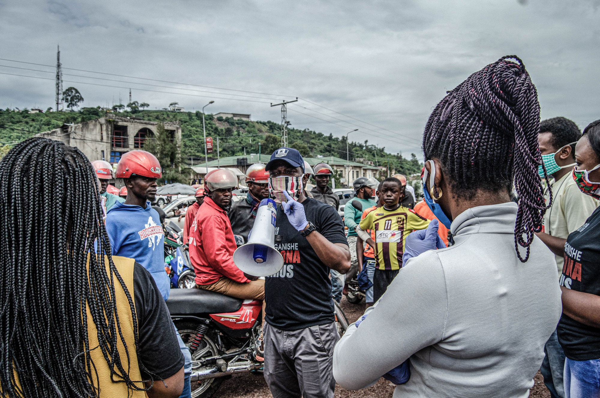 Goma, RDC, mai 2020. Des membres du collectif de bénévoles Goma Actif offrent des masques à des conducteurs de motos-taxis sur un carrefour du centre-ville. © Arlette Bashizi pour la Fondation Carmignac