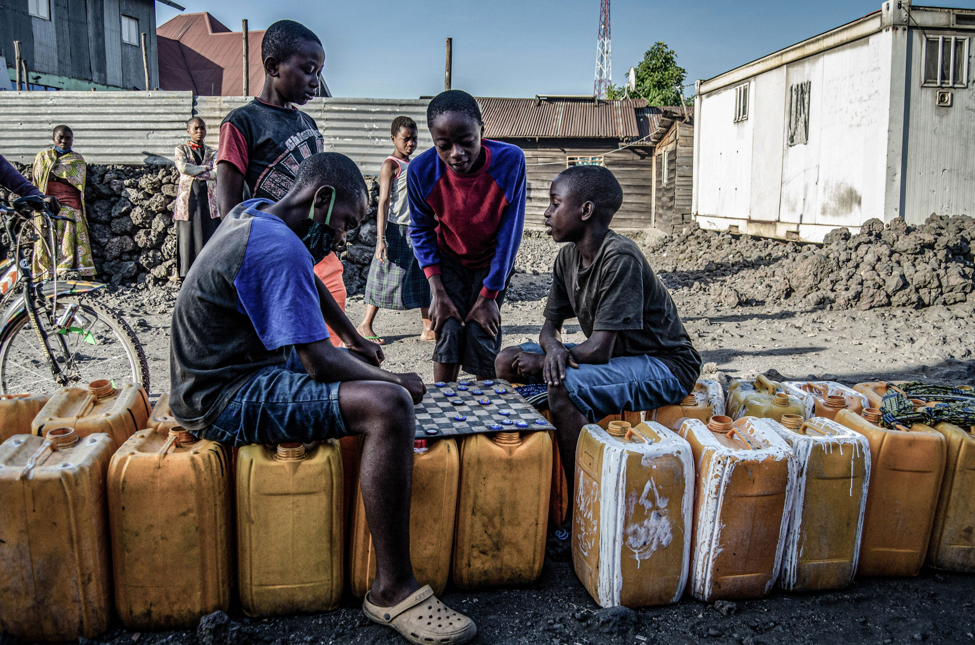 Goma, RDC, mai 2020. Des garçons jouent à un jeu de société en attendant de remplir leurs jerricans d’eau. © Arlette Bashizi pour la Fondation Carmignac