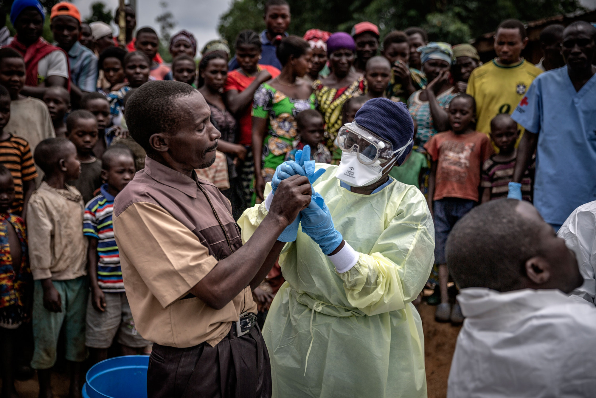 Rutshuru, province du Nord-Kivu, février 2020, un employé funéraire de la Croix-Rouge montre comment mettre des gants de protection avant l’examen du corps d’une enfant de 11 mois victime de l’épidémie d’Ebola. © Finbarr O’Reilly pour la Fondation Carmignac
