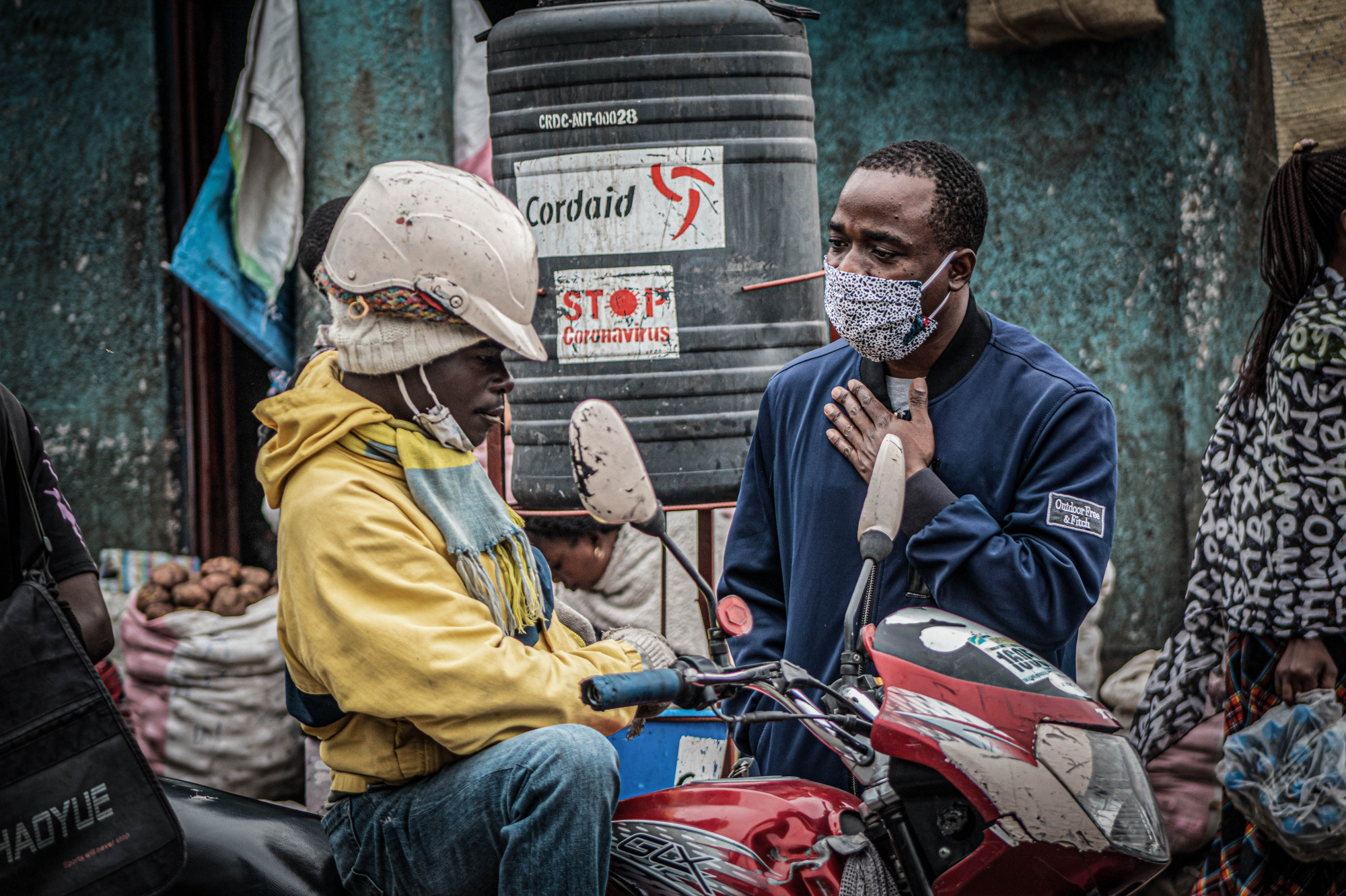 Goma, DRC, May 2020. Eugene Maisha Buingo, a member of Goma Actif, an independent, non-profit, apolitical and non-religious collective of young artists, musicians, journalists, and engaged citizens, speaks to a motorcycle taxi driver about coronavirus on the streets of the eastern Congolese city. © Arlette Bashizi for Fondation Carmignac