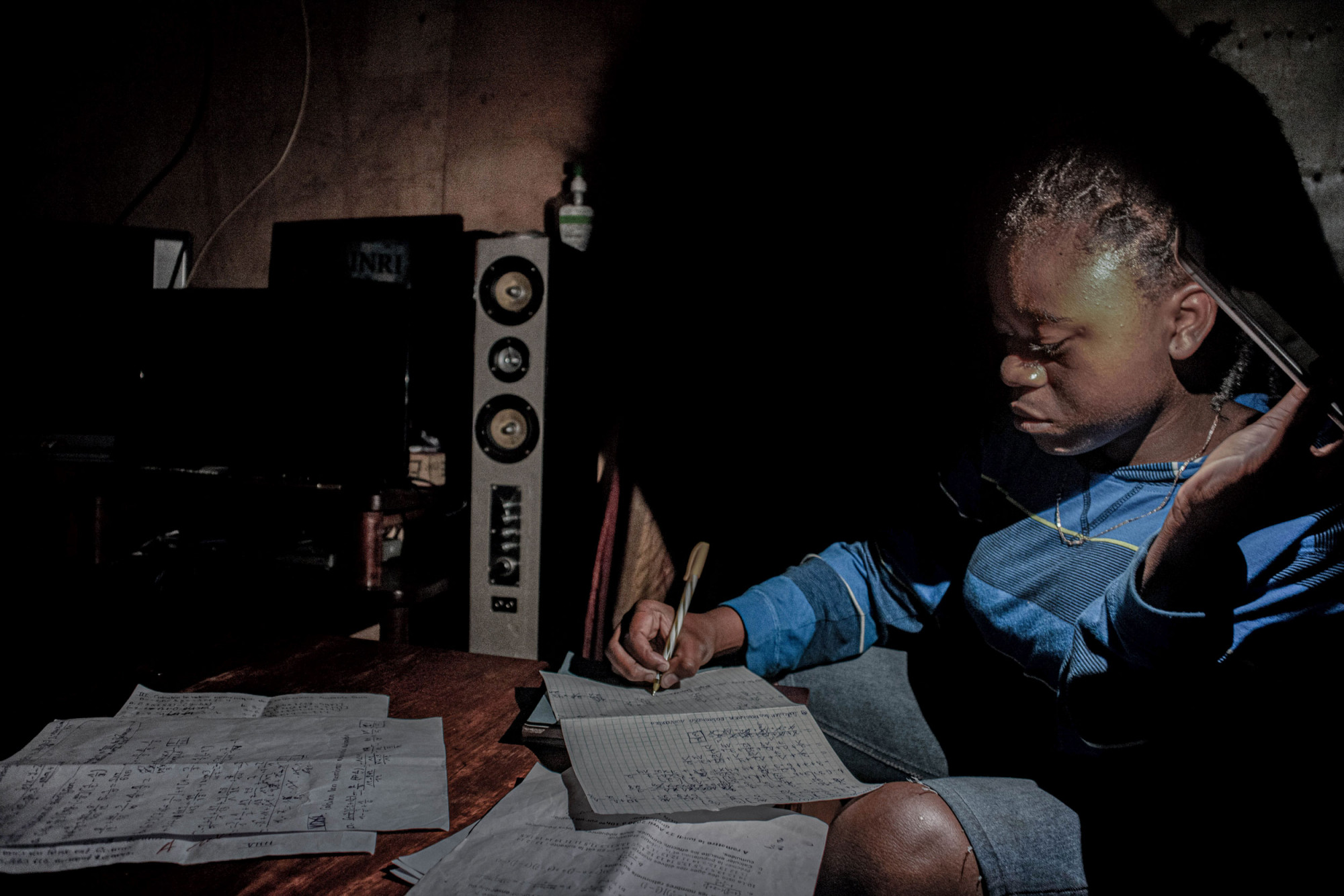 Goma, République démocratique du Congo, 27-28 avril 2020. Les écoles étant fermées pendant la période de confinement, et vu la régularité des coupures de courant dans la ville, ma petite sœur de 13 ans étudie à la maison en s’aidant de la torche d’un téléphone. © Arlette Bashizi pour la Fondation Carmignac