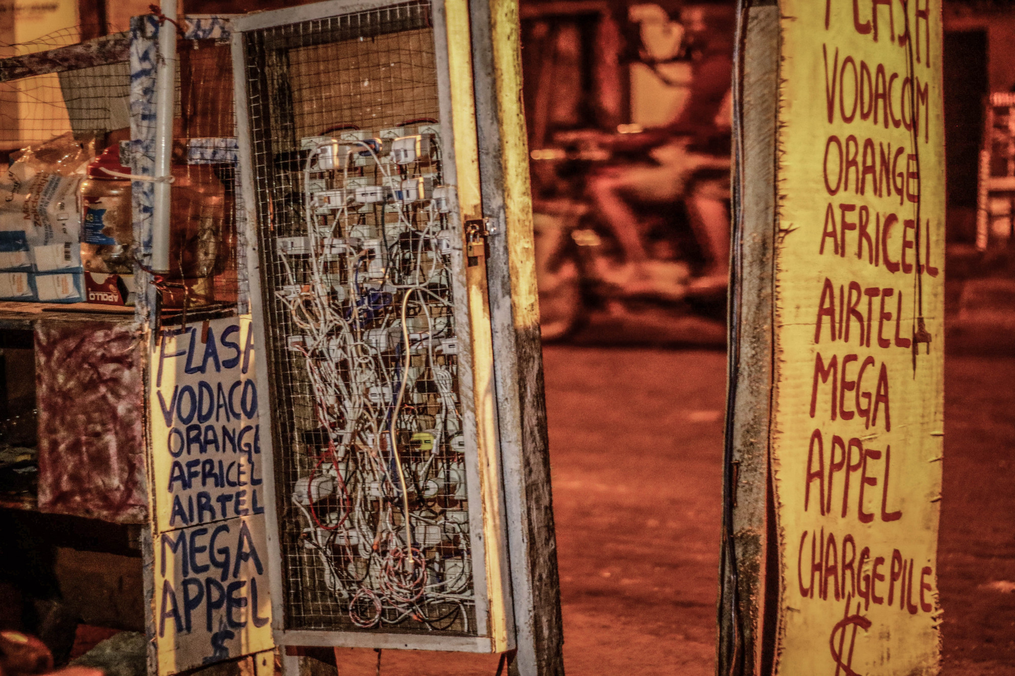 Kinshasa, RDC, mai 2020. Les kiosques publics vendent des cartes téléphoniques et disposent de rallonges électriques alimentées par générateur, terminées par des rangées de prises de courant sur lesquelles on peut recharger téléphones et ordinateurs pour l’équivalent de 1 à 2 $. © Justin Makangara pour la Fondation Carmignac