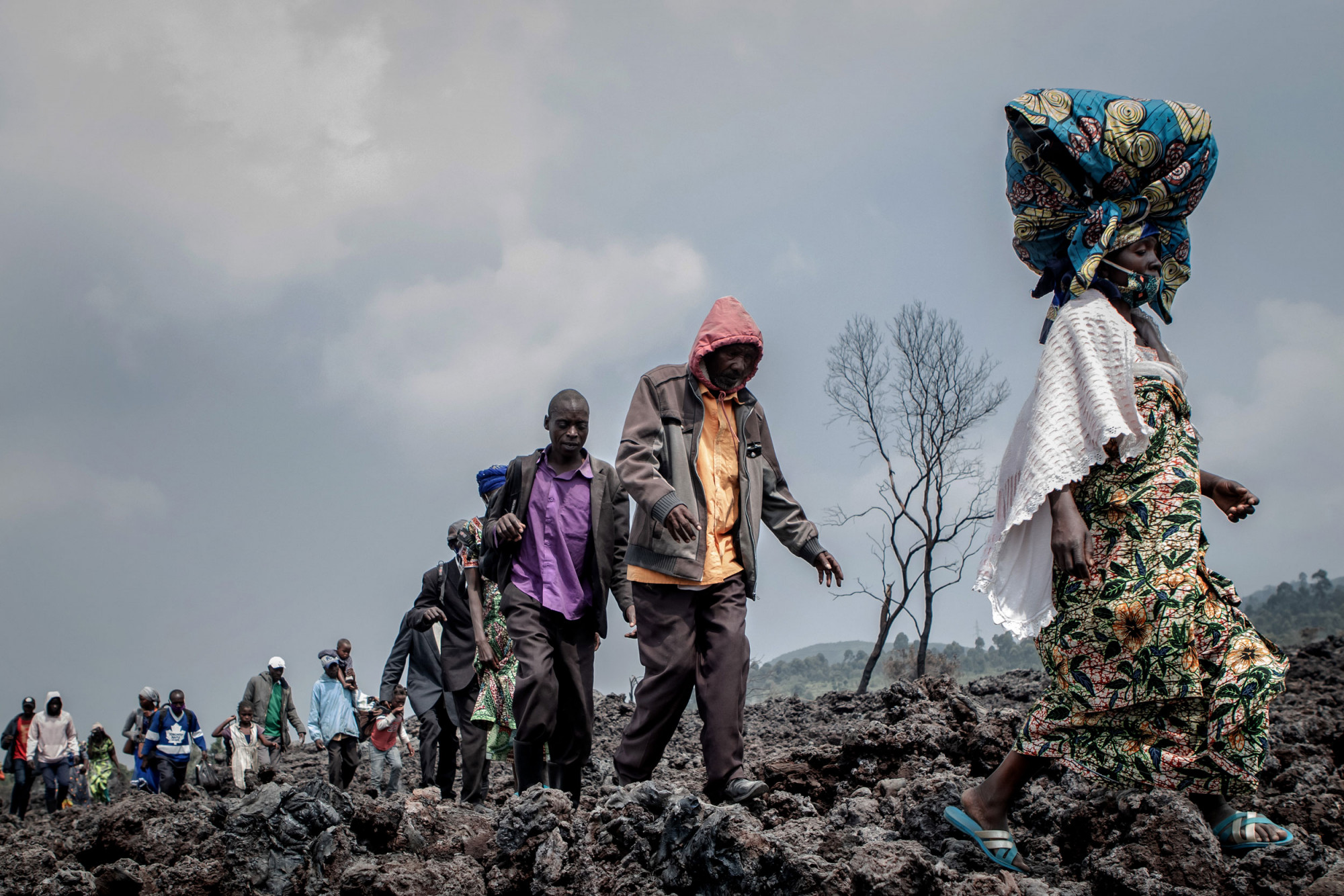 Goma, Nord-Kivu, 24 mai 2021. Des habitants traversent la lave refroidie à la recherche d’un endroit sûr, et d’autres transportent des marchandises vers le marché de la ville. © Guerchom Ndebo pour la Fondation Carmignac