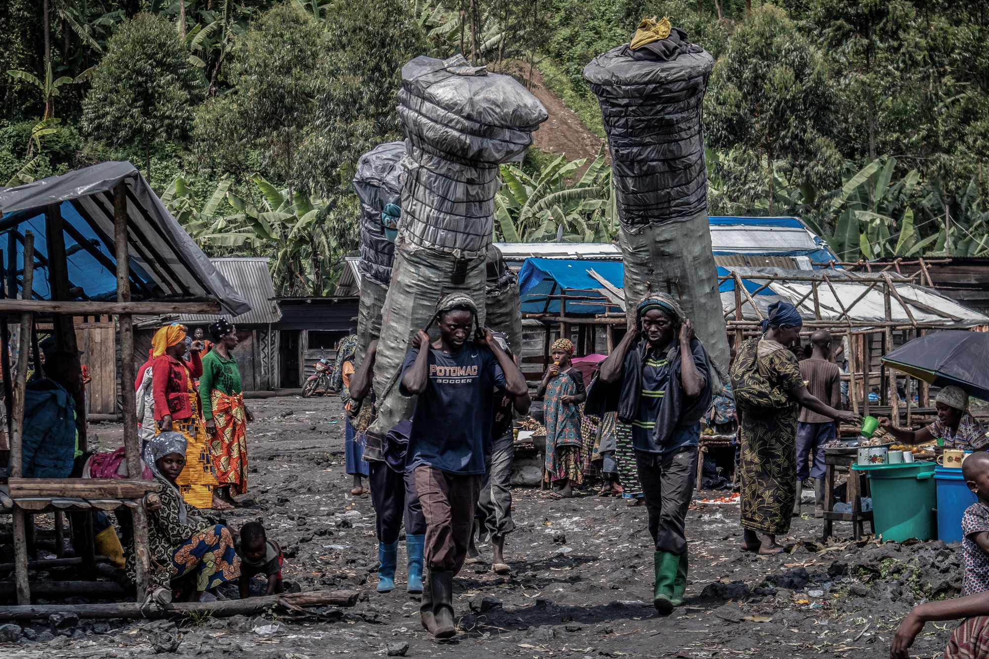 Parc national des Virunga, RDC, décembre 2020. Des hommes transportent du charbon de bois sur le marché rural de Kulupango. © Guerchom Ndebo pour la Fondation Carmignac