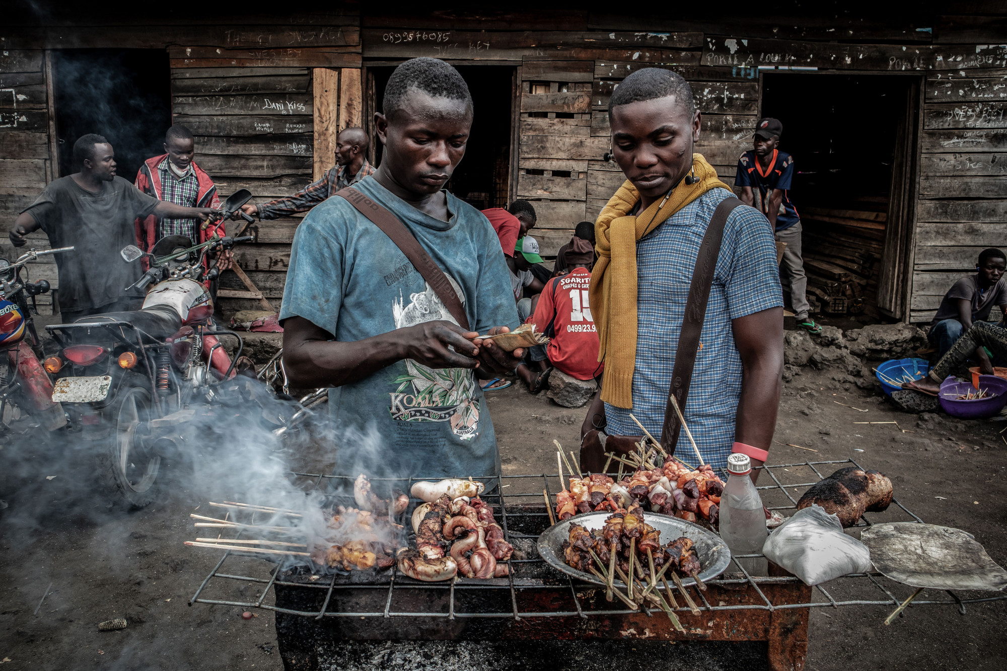 Environs de Goma, Nord-Kivu, RDC, décembre 2020. Balume Benjamin, 19 ans (à gauche), vend des brochettes cuites sur un grill à charbon de bois. © Guerchom Ndebo pour la Fondation Carmignac