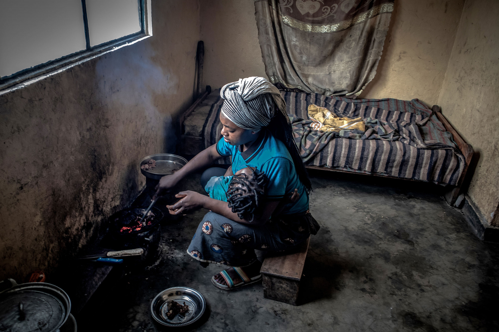 Minova, DRC, December 2020. Charmante prepares a meal on a charcoal stove inside her home. © Guerchom Ndebo for Fondation Carmignac
