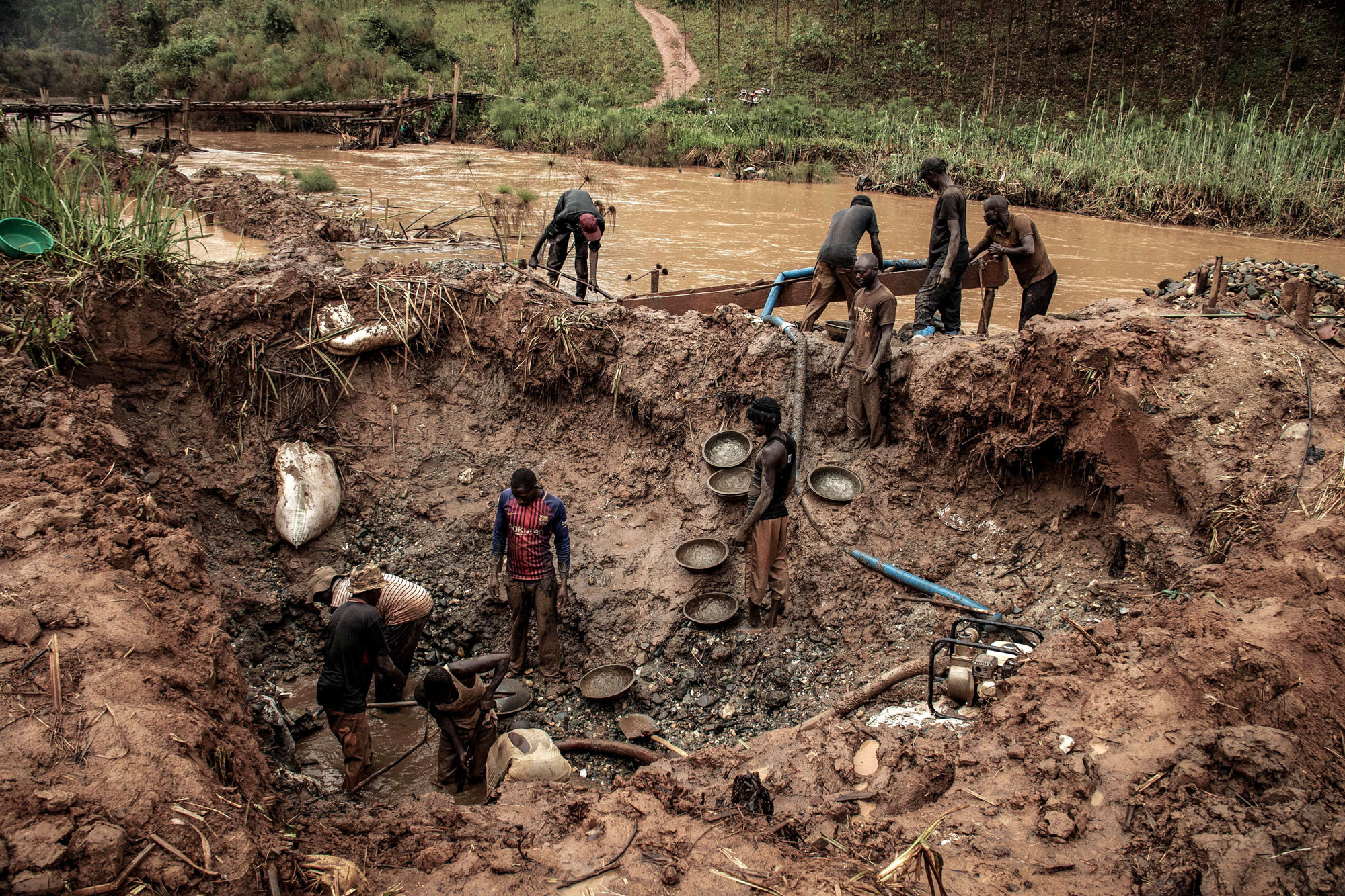 Bambissa, RDC, février 2020. Des orpailleurs extraient l’or des sédiments alluviaux de la rivière Nizi. La plupart des massacres en Ituri ont leur origine dans la compétition pour les mines d’or, selon l’ONG Human Rights Watch. Les mines locales sont une source de financement pour les ex-rebelles, les politiciens et les hauts gradés congolais faisant la contrebande de l’or dans les pays voisins, l’Ouganda et le Sud-Soudan. Le minerai est extrait par des coopératives artisanales utilisant des outils et des techniques rudimentaires. La plupart d’entre elles, à l’instar des compagnies minières, ne rapportent pas leurs chiffres de production et de grandes quantités de minerais sont ainsi mises illégalement sur le marché, ce qui crée une « fraude massive », écrit l’agence Reuters. Mais les mesures prises pour endiguer l’épidémie de coronavirus ont rompu les chaînes d’approvisionnement dont dépendent les orpailleurs et asséché leurs sources financières, causant un effondrement des prix locaux de l’or, jusqu’à 40 % du cours mondial. Dans une seule zone de l’Ituri, 70 des 85 négoces en or ont fermé faute d’acheteurs, note l’ONG canadienne Impact, spécialisée dans les ressources naturelles. © Dieudonné Dirole pour la Fondation Carmignac