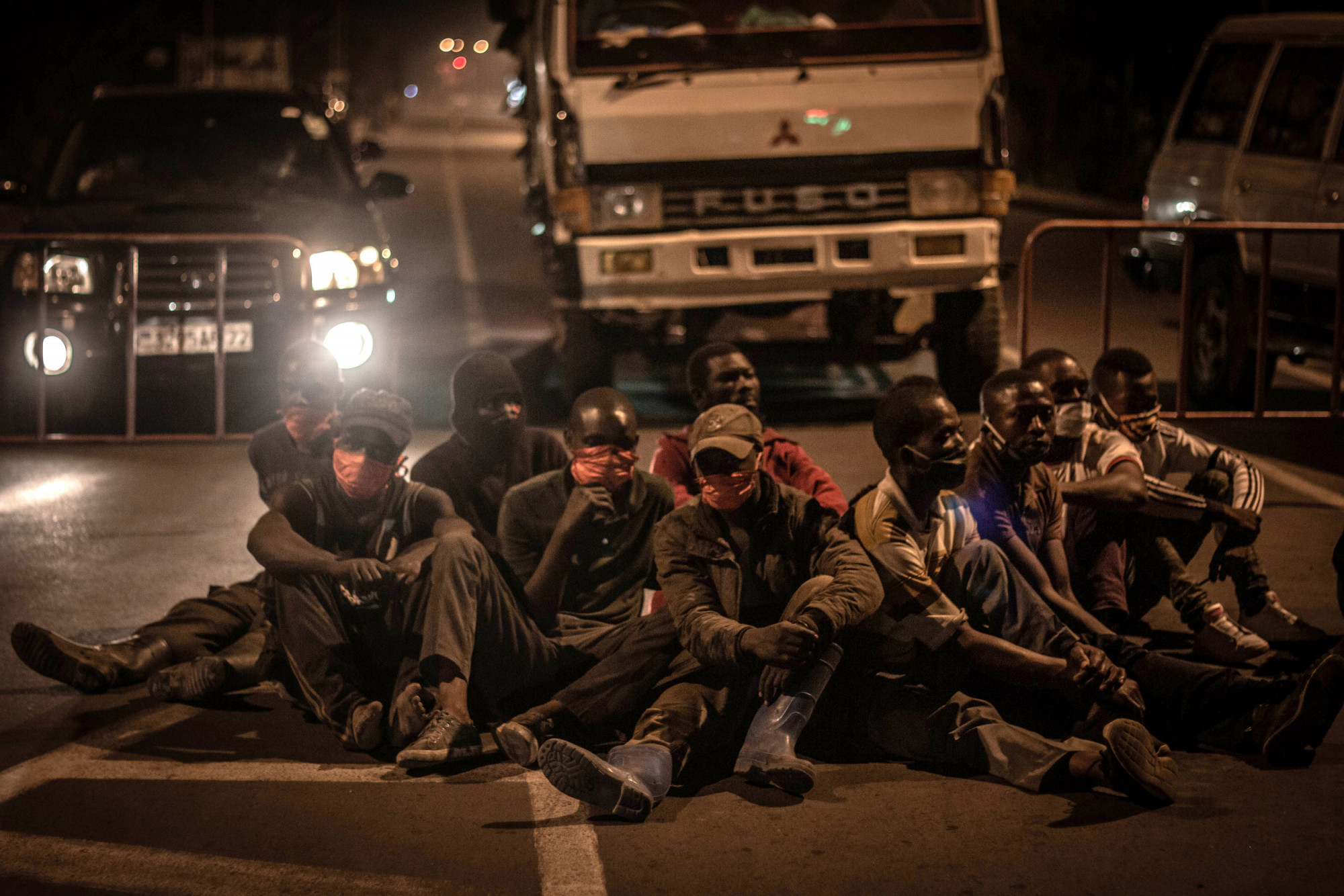 Goma, RDC, 20 mai 2020. La police a forcé ces hommes à s’asseoir par terre pour avoir enfreint le nouveau couvre-feu imposé afin d’endiguer la propagation du coronavirus dans la métropole de l’est du Congo. © Guerchom Ndebo pour la Fondation Carmignac