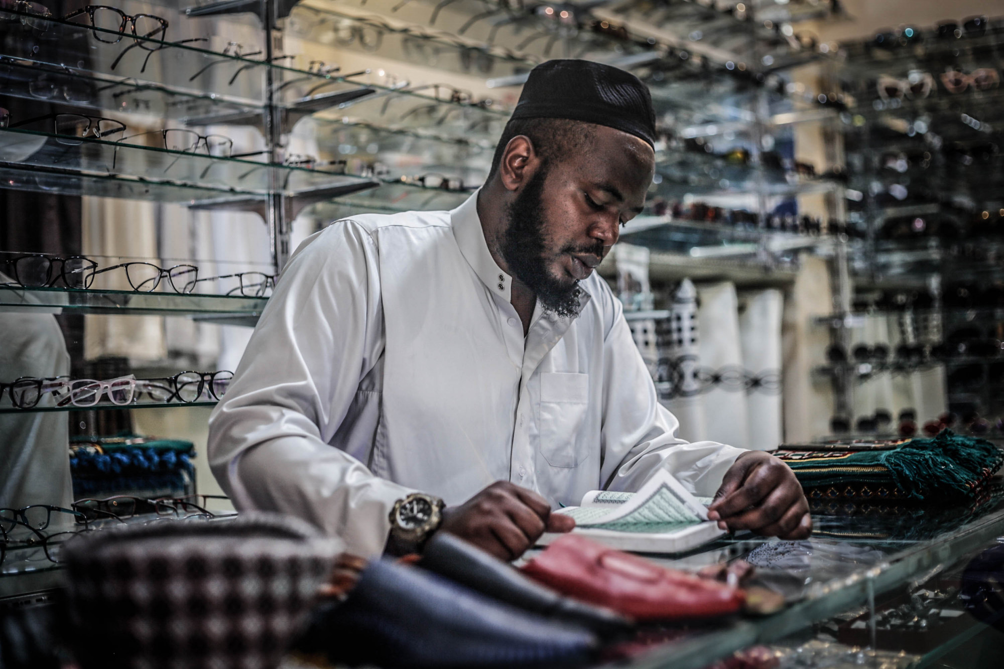 Goma, DRC May 2020. A man reads the Koran in his eyeglasses shop in Goma during Ramadan. © Ley Uwera for Fondation Carmignac